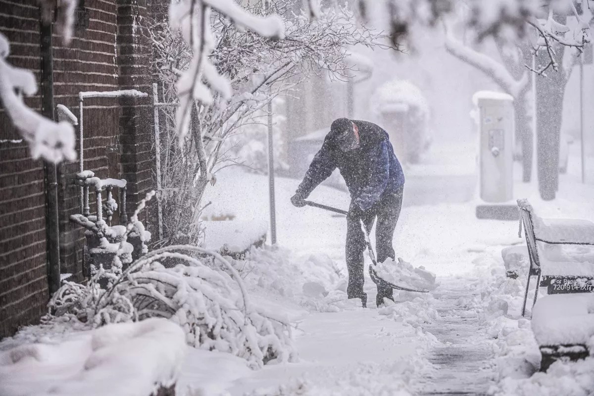 Man shovels snow on the sidewalk in Denver