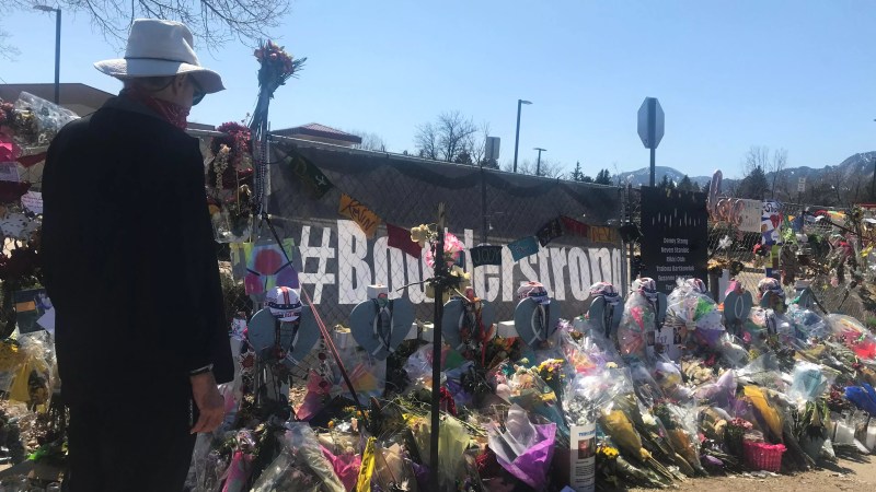 A banner with the words #BoulderStrong surrounded by flowers aand other mementos.