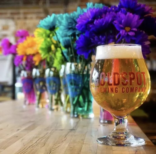 a glass of beer in front of rainbow flowers
