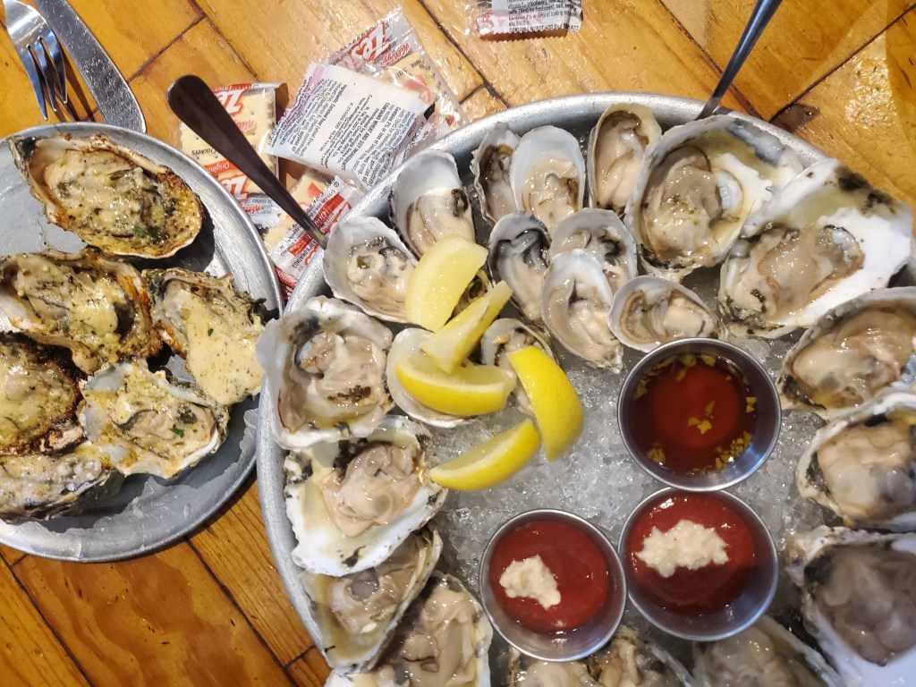 a platter of raw oysters next to grilled oysters on a plate