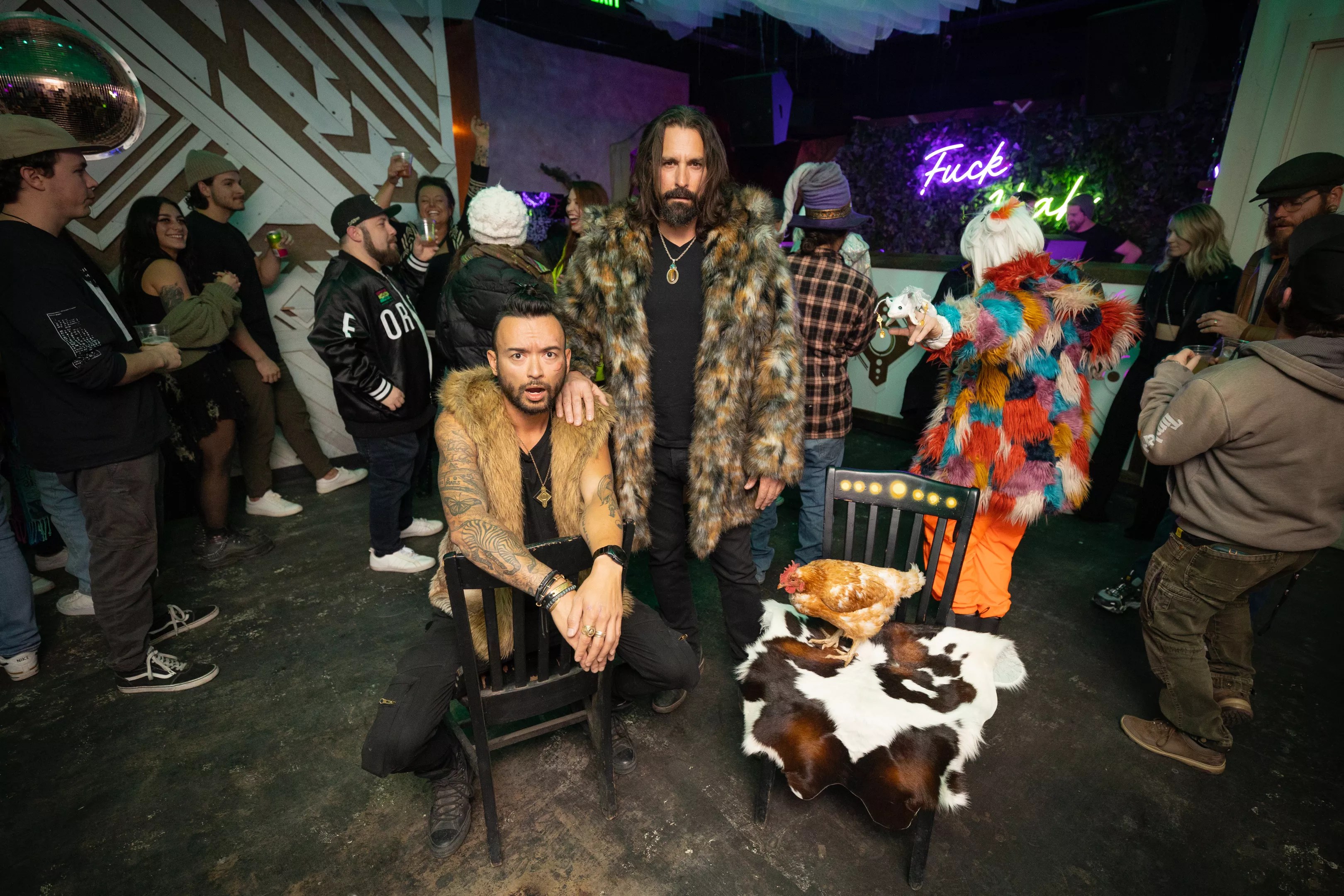 two men in fur coats stand in a club