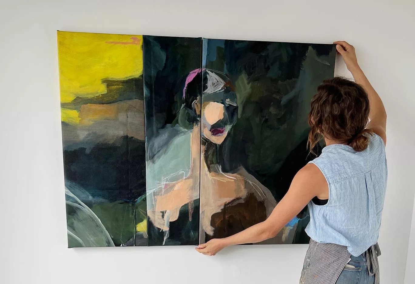 woman hanging a painting