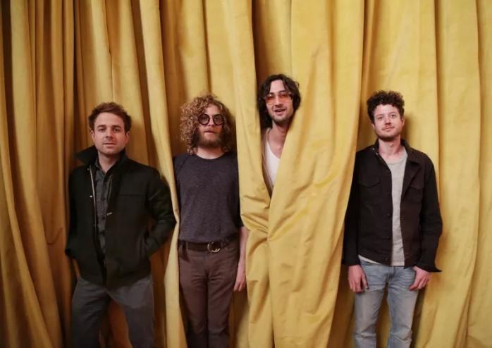 Four musicians in front of yellow curtain