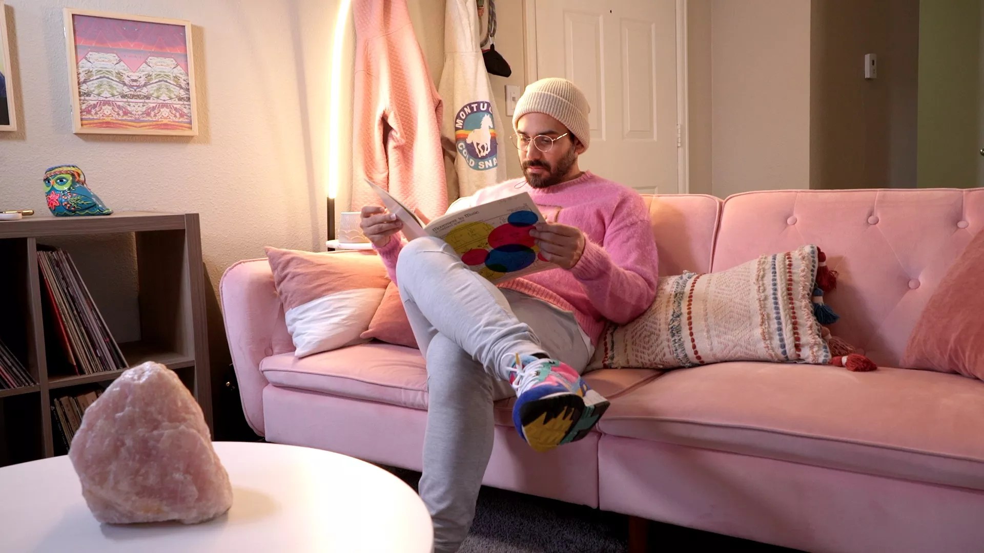 man in pink shirt reads book on pink sofa