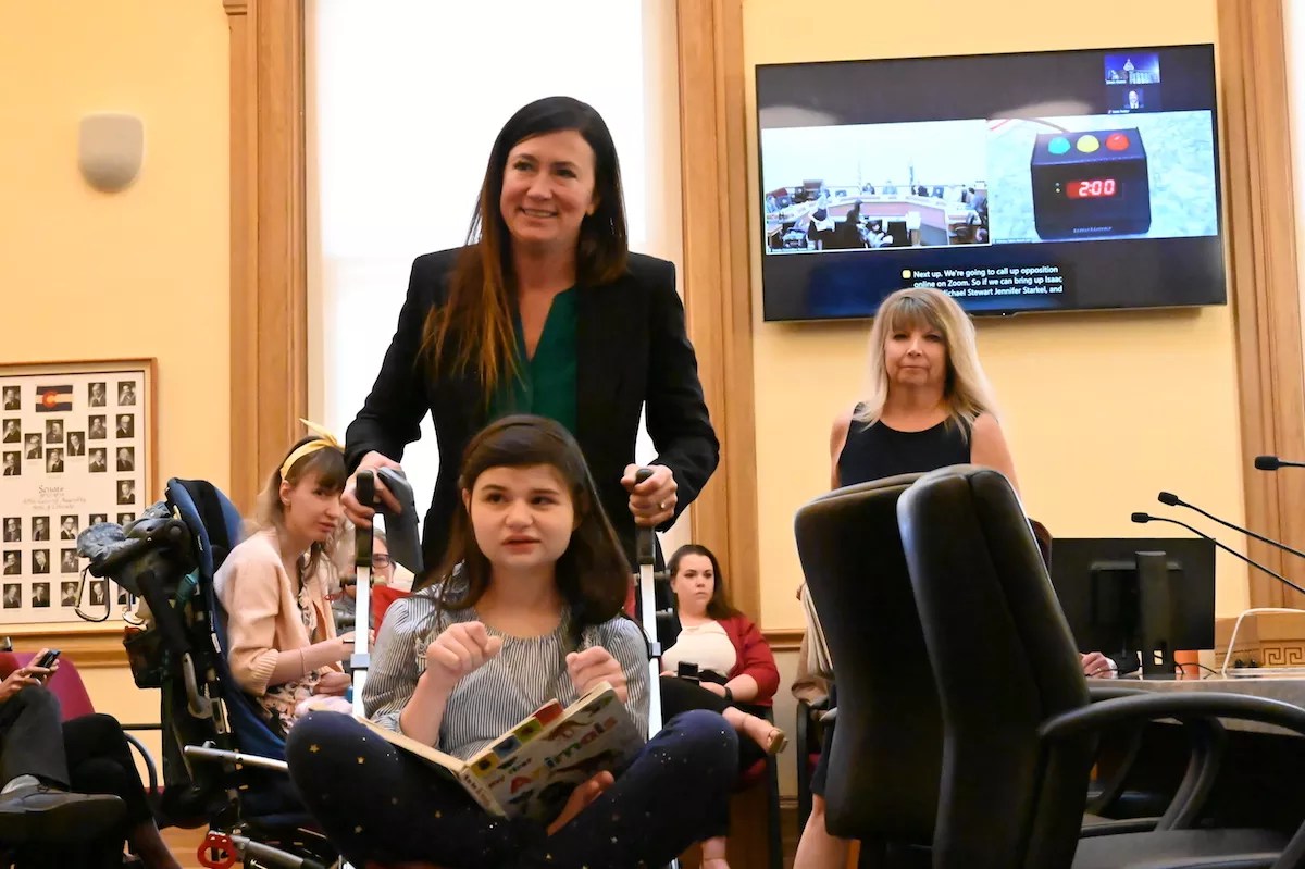Liz Cochran walks away from the panel after testify before the Senate Finance Committee about the importance of CBD products for her disabled daughter, who is in the wheelchair in front of her.
