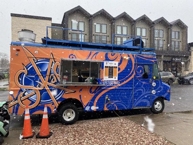 a food truck with a blue and orange wrap.
