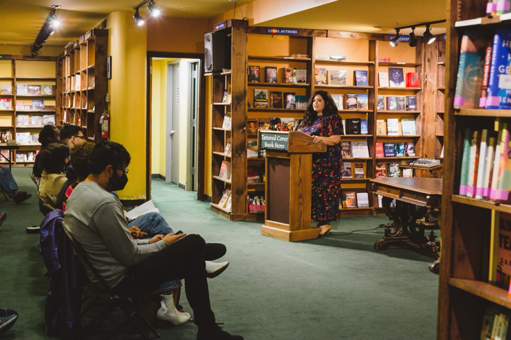 woman reading at a podium in a bookstore