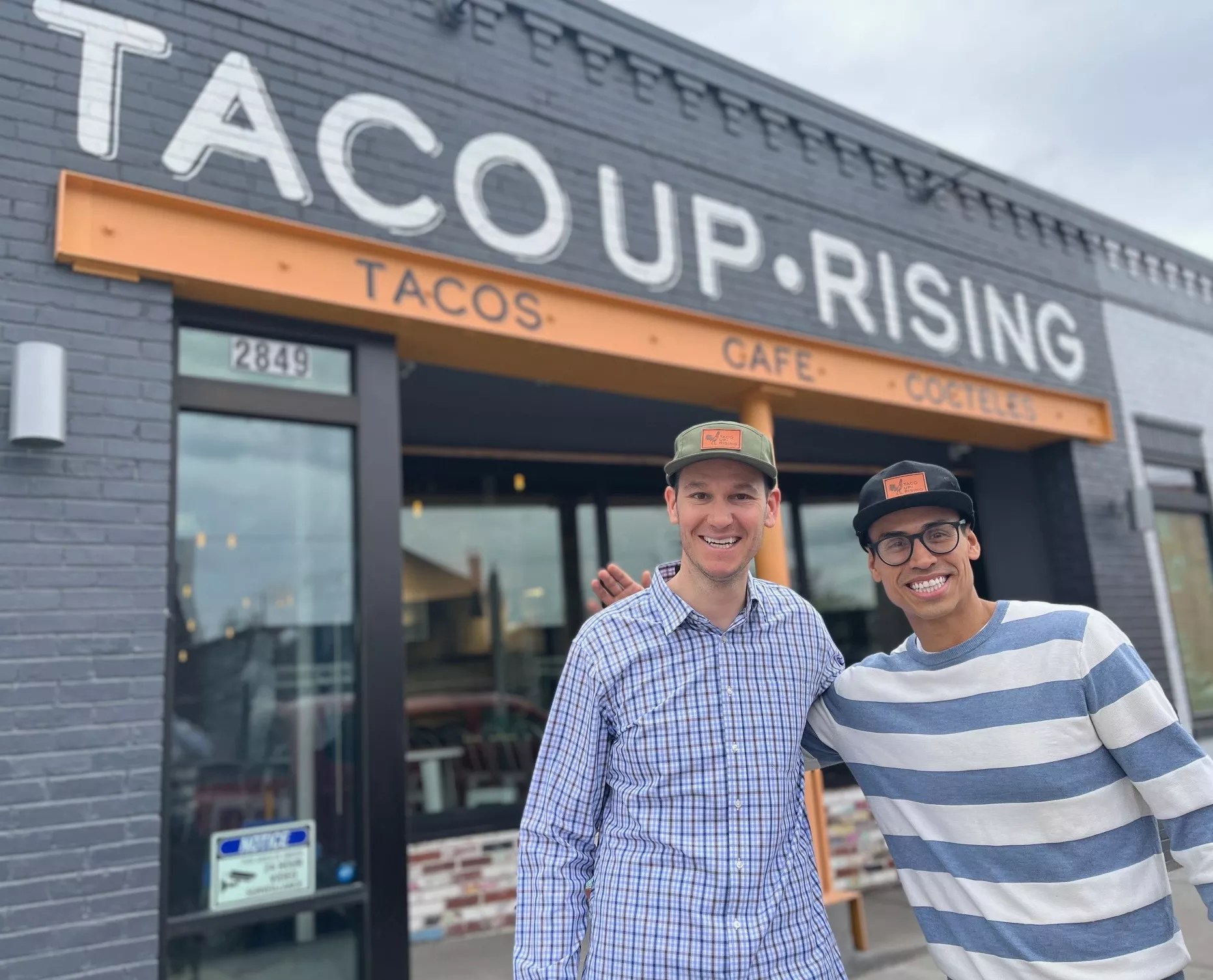 Two men stand outside taco restaurant