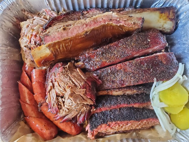 a pan of barbecue ribs, sausages, pulled pork and brisket