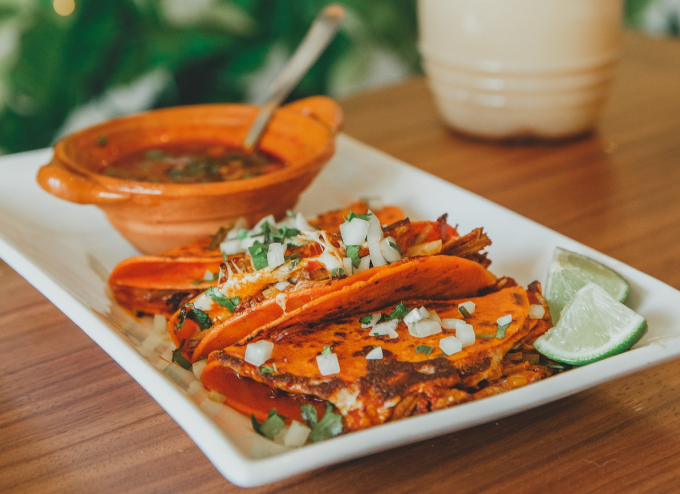 a plate of tacos with onions and cilantro on top