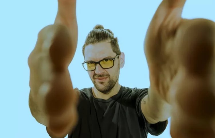 man in yellow sunglasses framing camera lens with hands