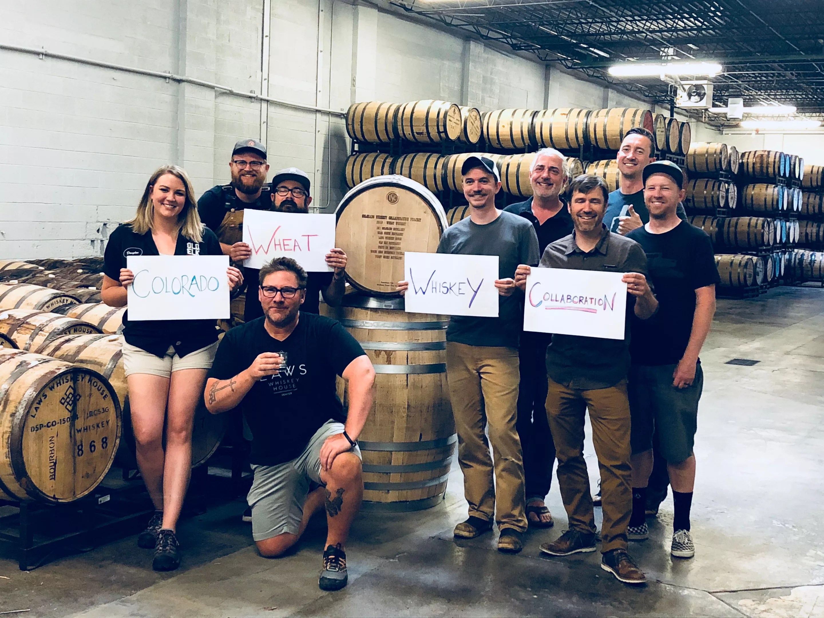 a group of people stand around whiskey barrels holding signs