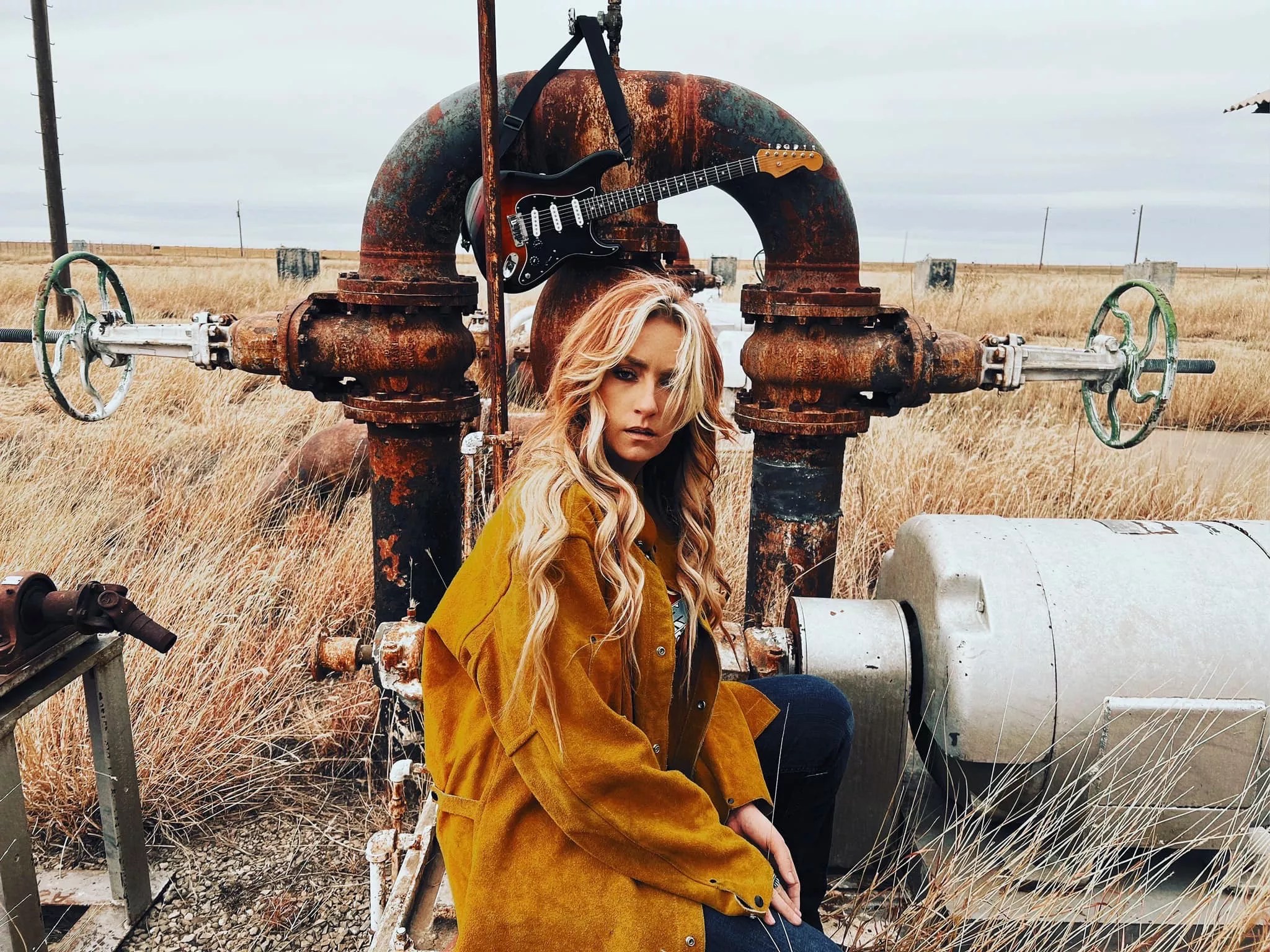 blonde woman crouches in a field