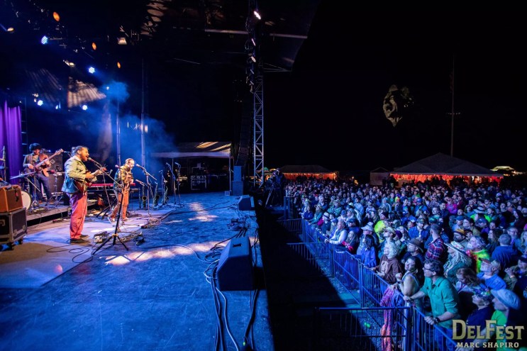 a band plays on stage to an outdoor crowd at night