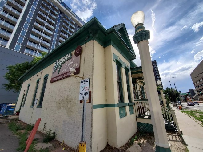 the corner view of a white building with green trim