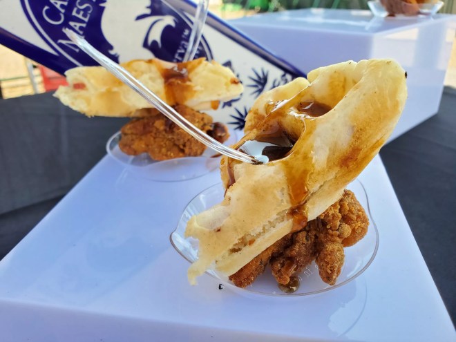a piece of waffle over fried chicken with syrup