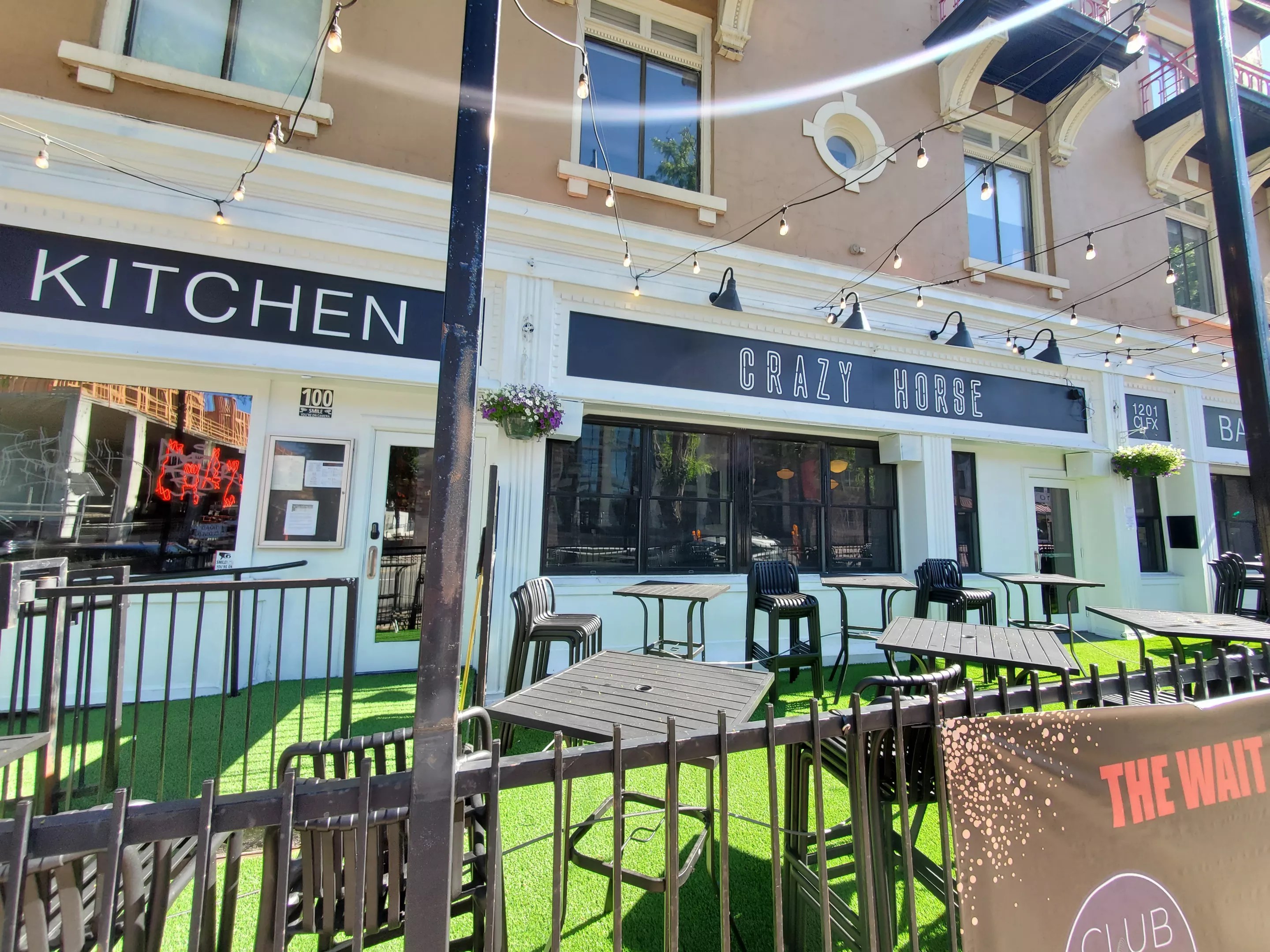 the front of a white building with green turf on the patio