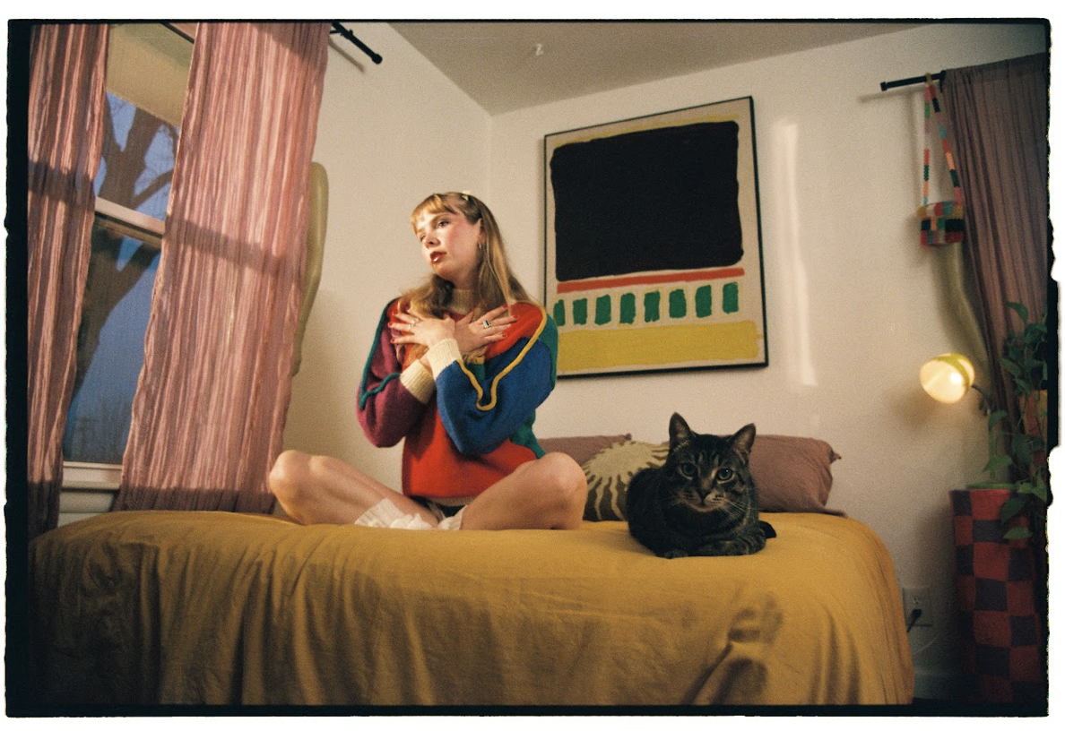 woman sits on bed with black cat