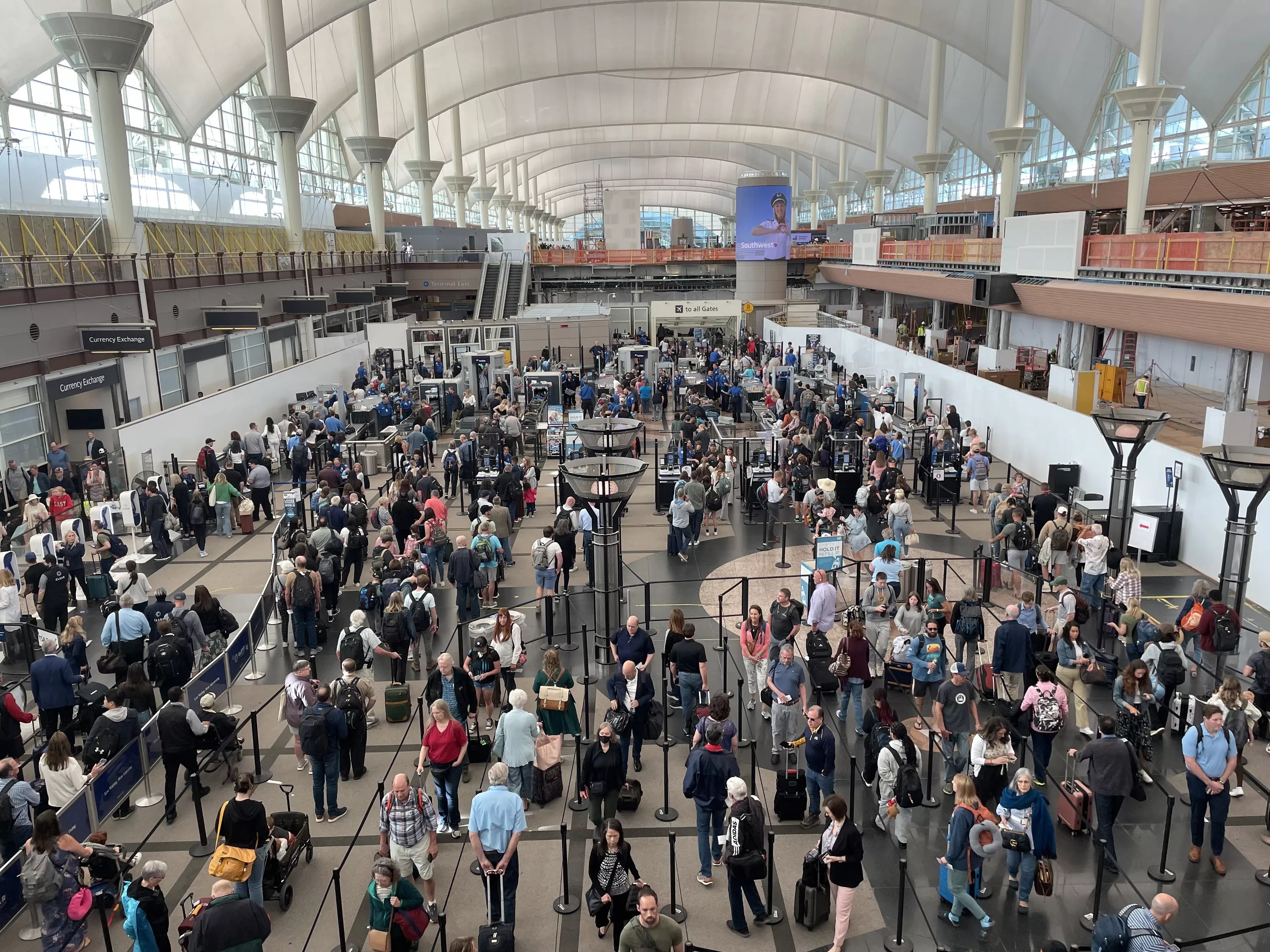 People wind their way through a security line in a hall with a domed roof.