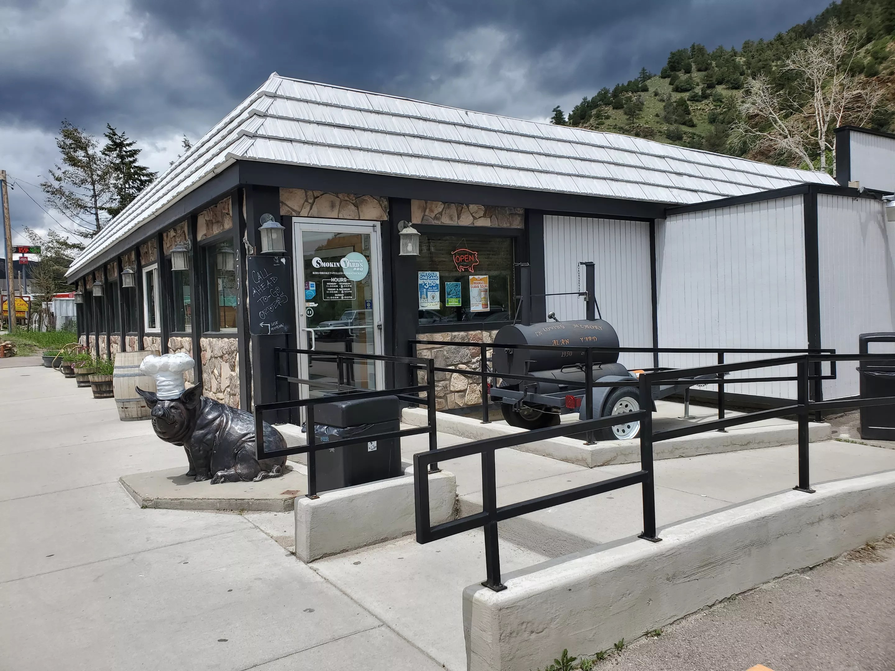 a small building with a pig sculpture and a smoker out front