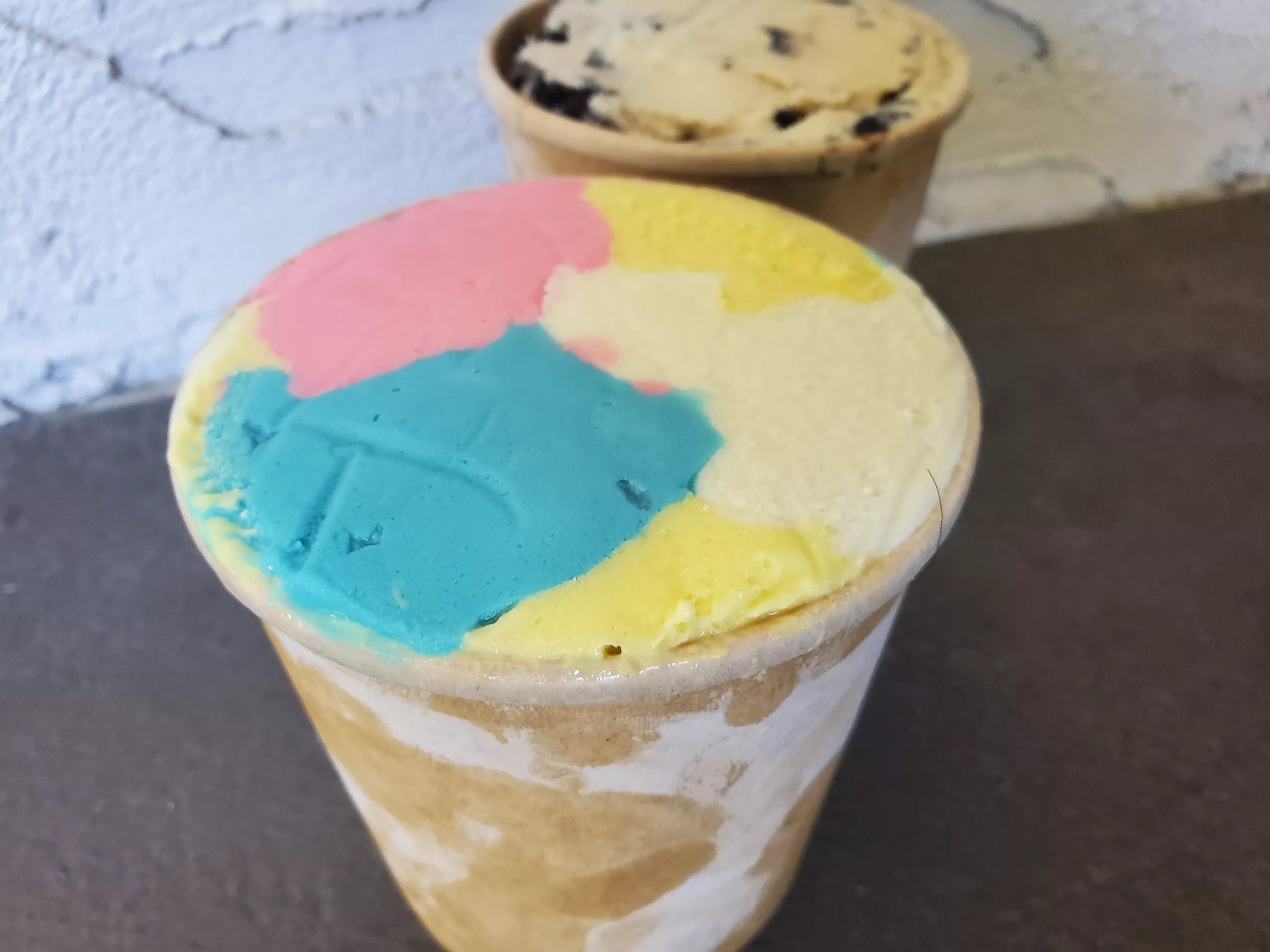 a pint of rainbow sherbet in front of another pint of ice cream