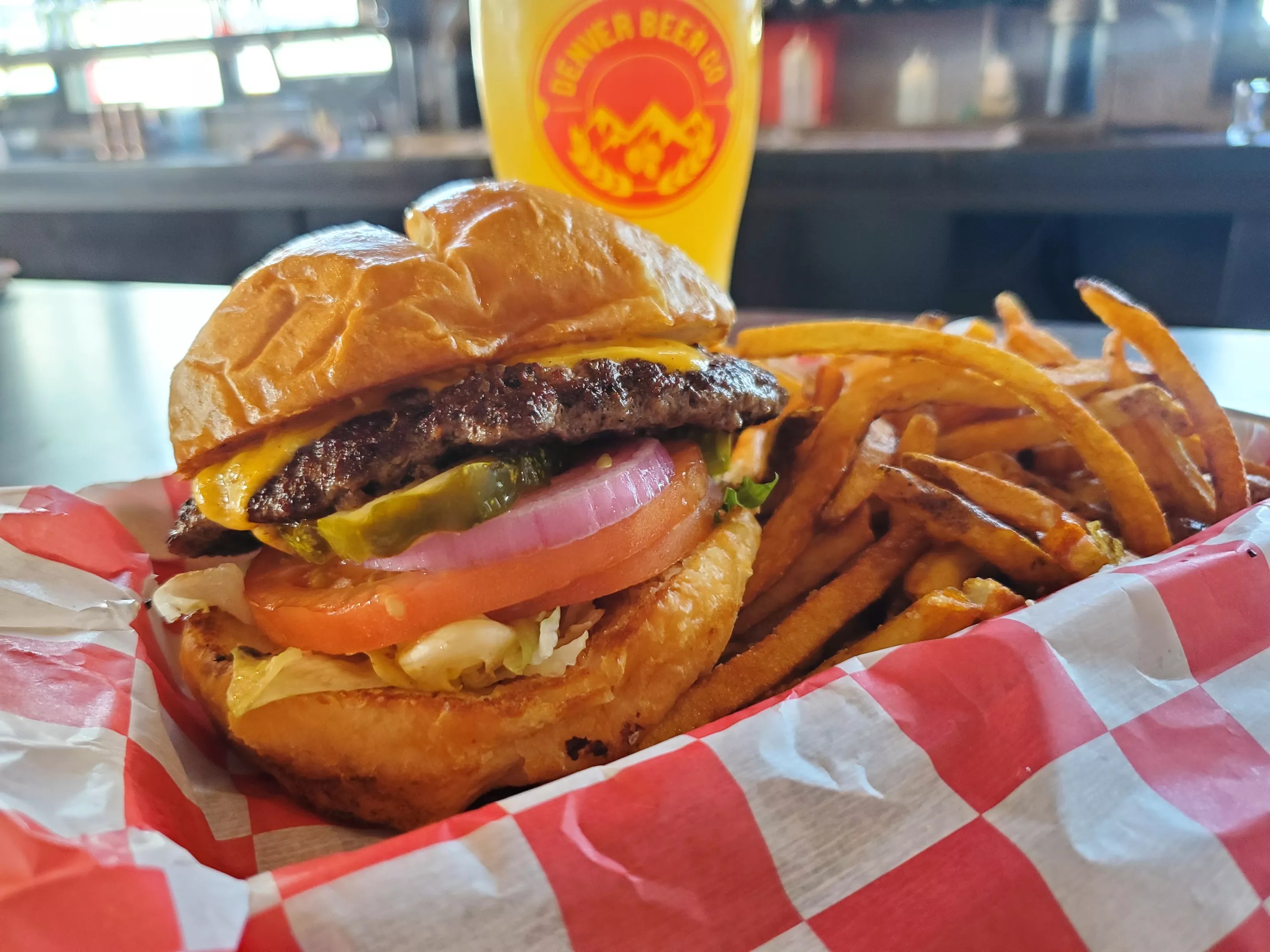 a cheeseburger in front of a pint glass of beer