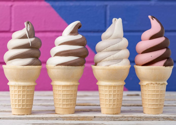 four soft serve ice cream cones in front of a blue and pink wall