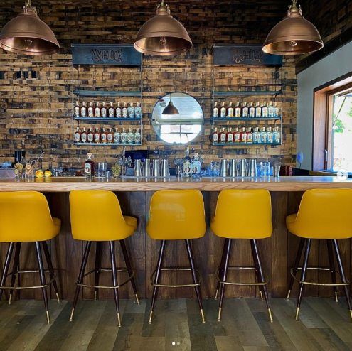 yellow stools lined up in front of a wooden bar