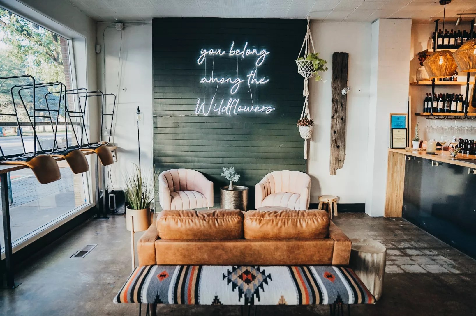 a couch and chairs in front of a wall with a neon sign