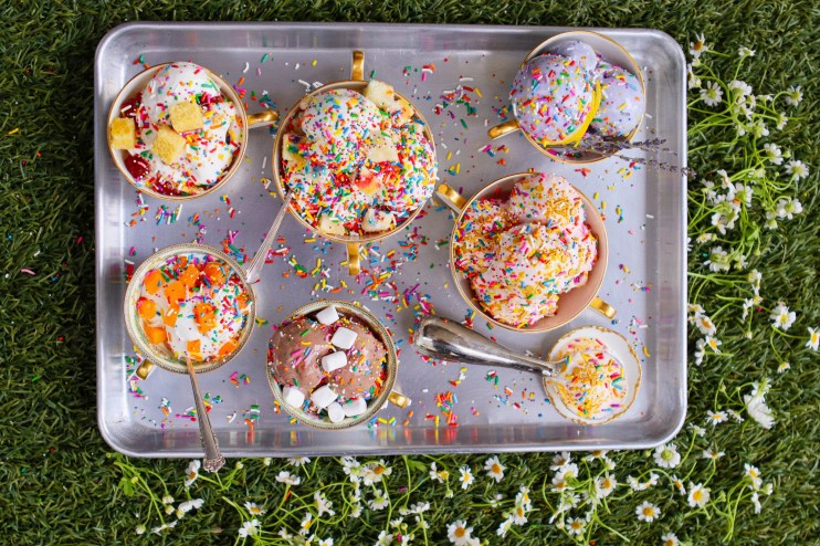 an overhead shot of scoops of ice cream in cups covered in sprinkles