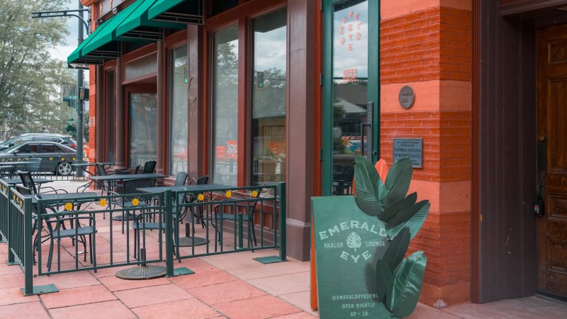 a green sign in front of the entryway of a brick building