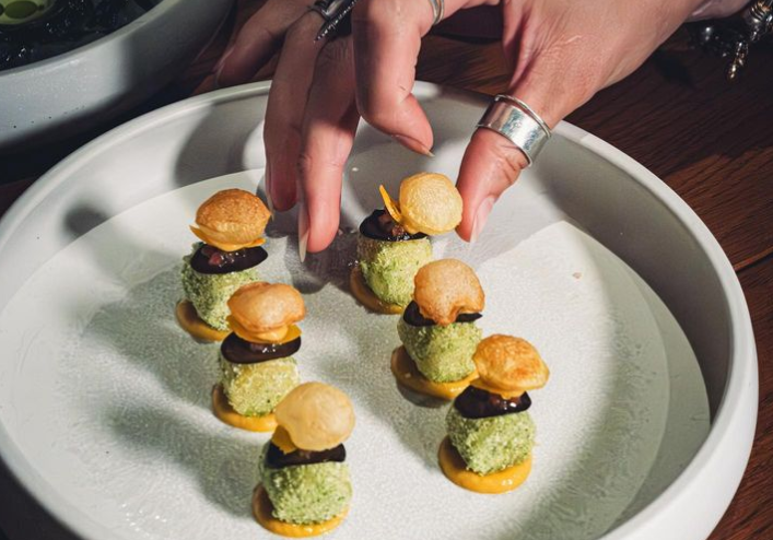 a hand reaching for a small appetizer on a place