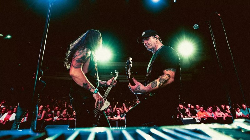 two men playing bass and guitar on stage