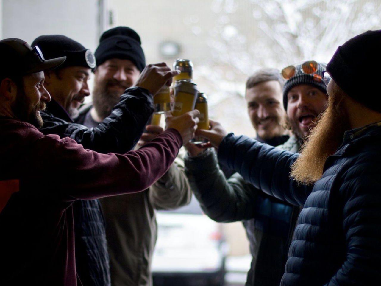 men in jackets holding pints of beer
