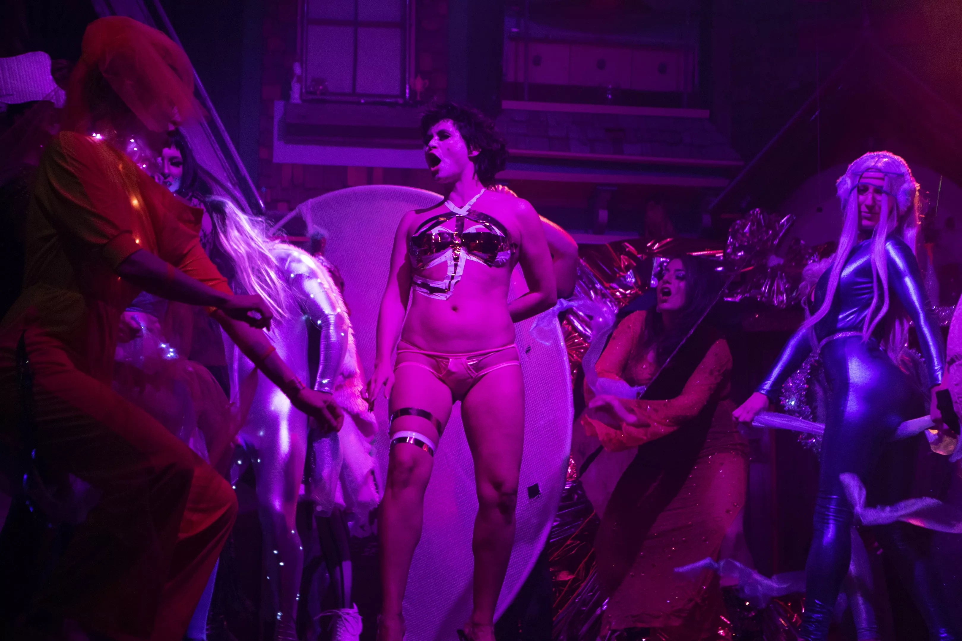 drag performers on stage with purple lighting.