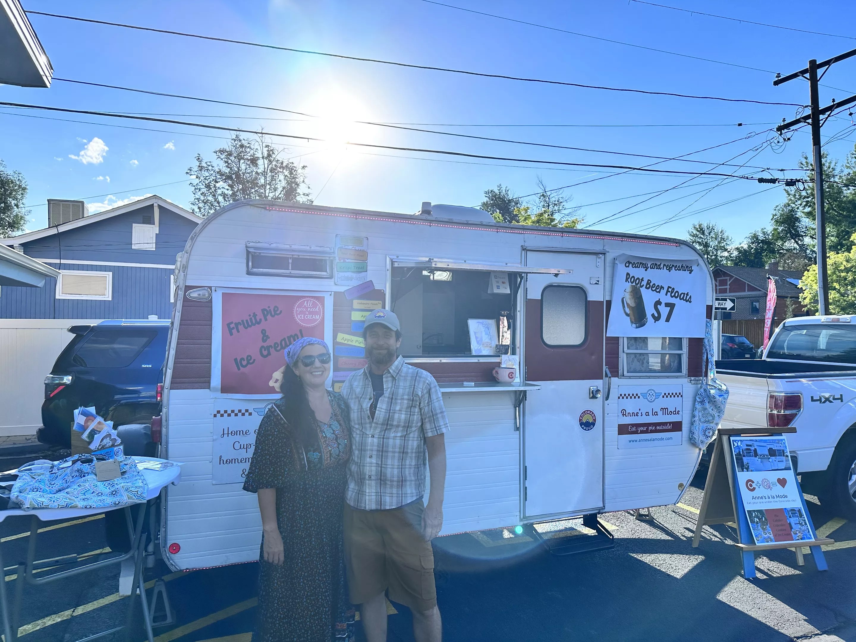 a man and a woman stand in front of a mobile food trailer