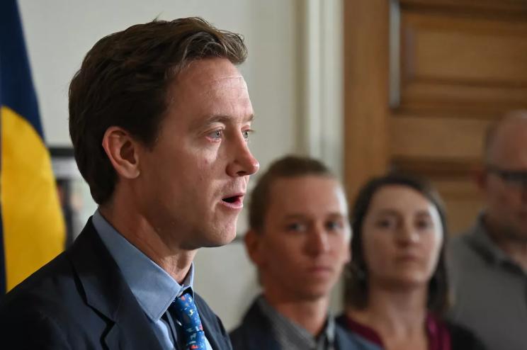 Mayor Mike Johnston speaks with Cole Chandler on his side.