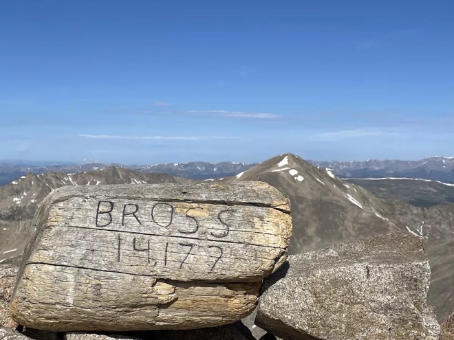 An carved log showing Mt. Bross' elevation and the neighboring Mt. Democrat in the background.