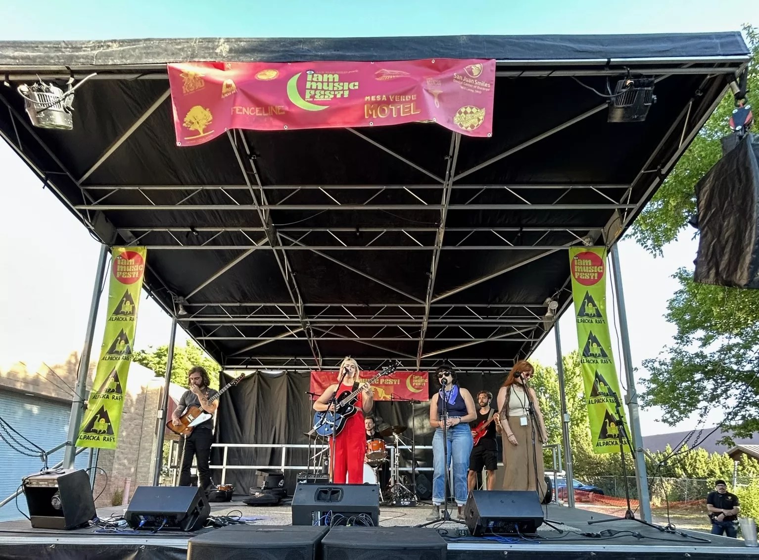 three women on outdoorstage with other musicians