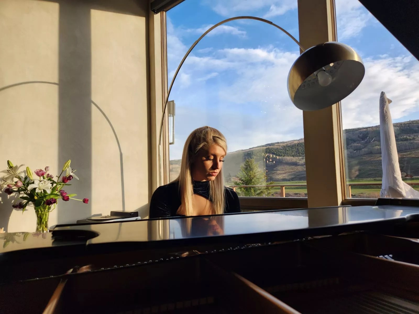 blonde woman playing a baby grand piano.