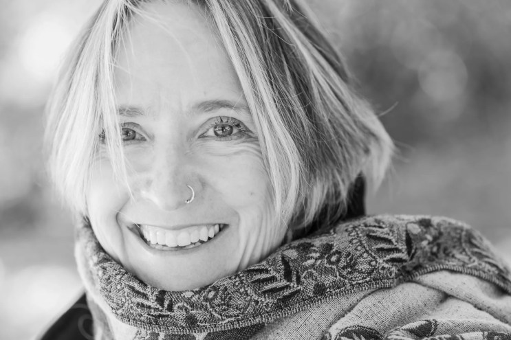 a black and white photo of a smiling blonde woman wearing a scarf