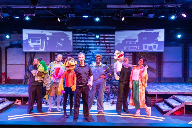 actors stand on stage holding puppets