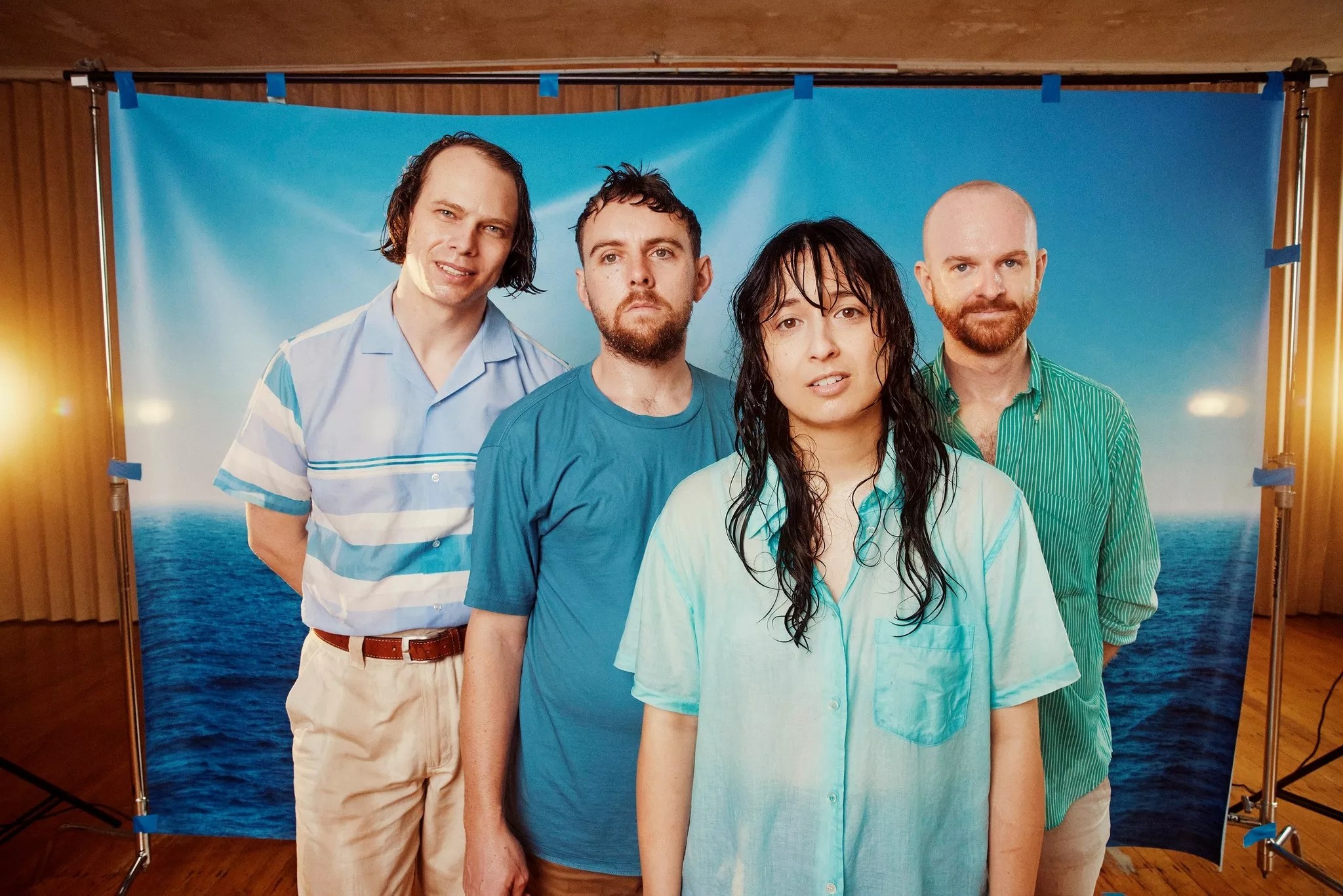 a man in a blue striped polo, a man in a blue t-shirt, a woman in a blue collared shirt and a man in a teal collared shirt.