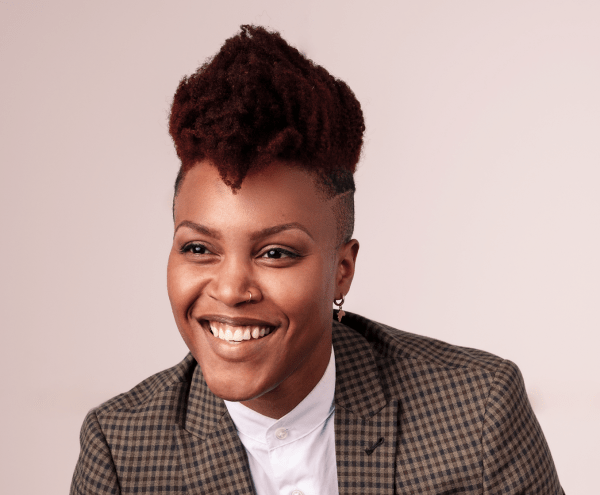 black woman smiling in a suit jacket over a white shirt