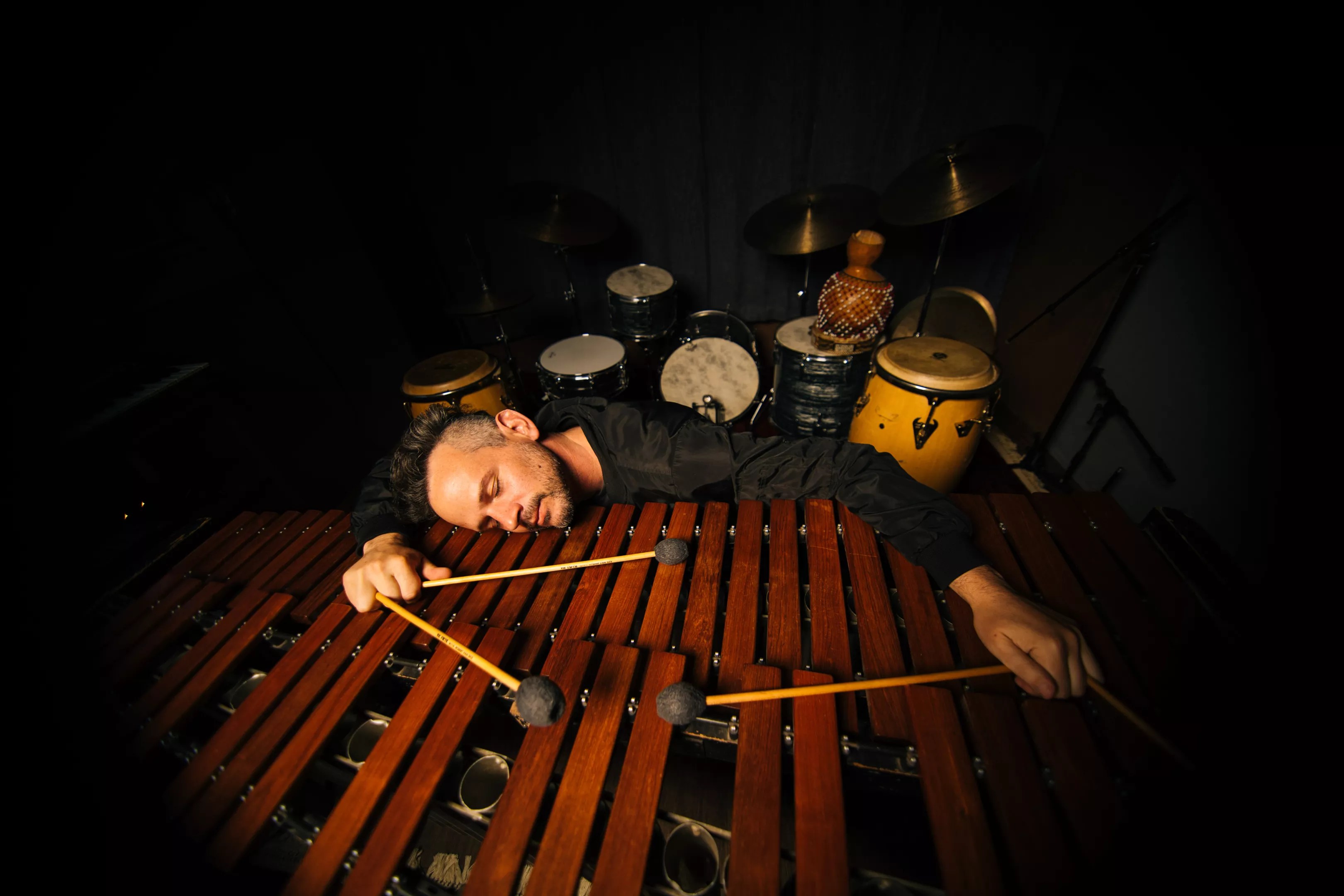 a man lies down with drum sticks