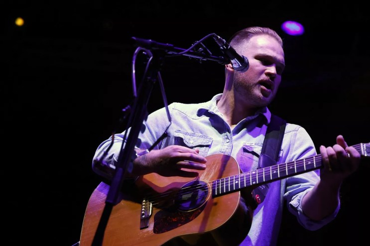 man playing guitar in button-up shirt