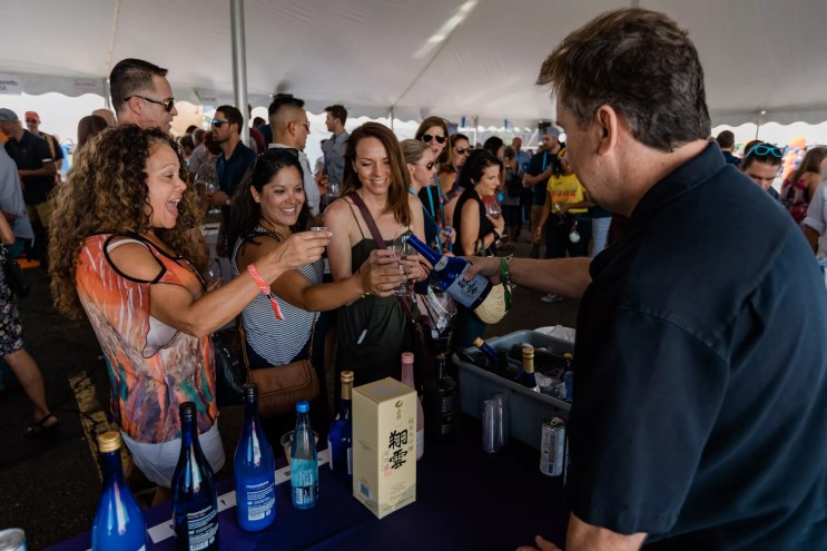 people at a booth where a man is pouring wine