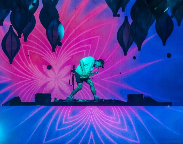 man with saxophone on stage with pink and blue lights