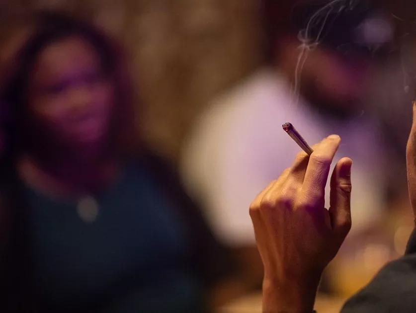 A hand holds a burning joint