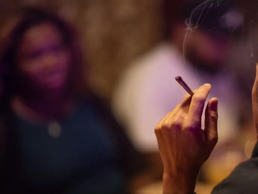 A hand holds a burning joint